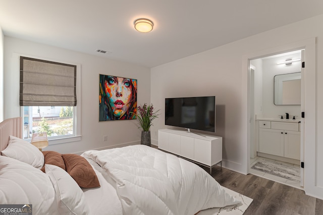 bedroom with connected bathroom, sink, and dark hardwood / wood-style flooring