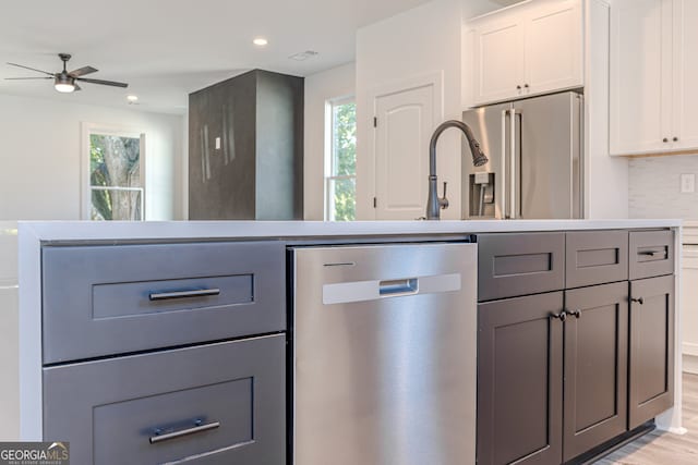 kitchen with a wealth of natural light, appliances with stainless steel finishes, and white cabinets