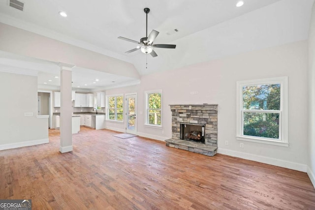 unfurnished living room featuring a fireplace, ceiling fan, light wood-type flooring, and a wealth of natural light