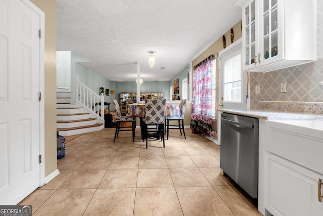 kitchen featuring light tile patterned floors, backsplash, white cabinets, a textured ceiling, and stainless steel dishwasher