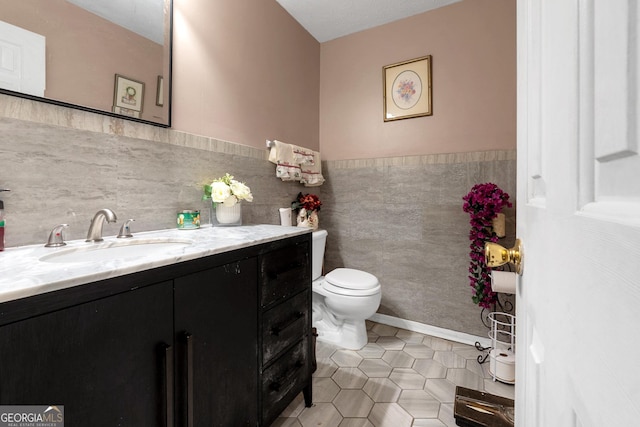 bathroom with tile patterned floors, toilet, vanity, and tile walls