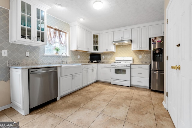 kitchen featuring backsplash, white cabinets, light tile patterned floors, stainless steel appliances, and a textured ceiling