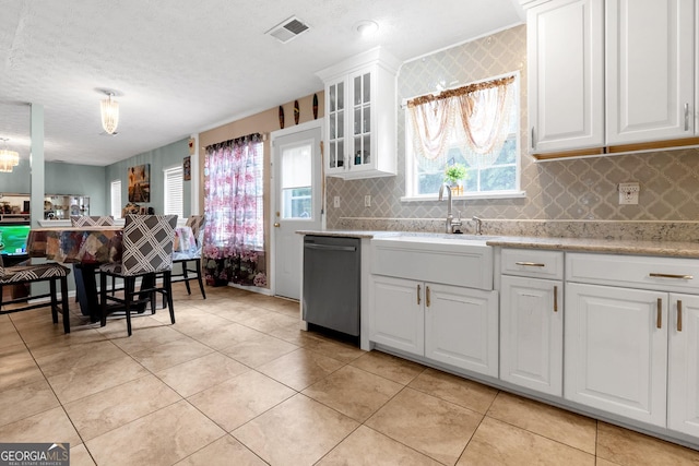 kitchen with tasteful backsplash, white cabinetry, dishwasher, light tile patterned floors, and a textured ceiling