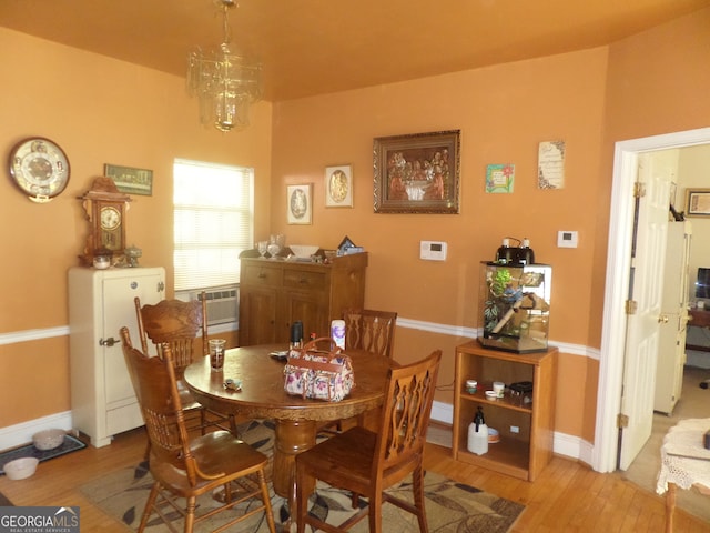 dining room with cooling unit, light hardwood / wood-style flooring, and an inviting chandelier