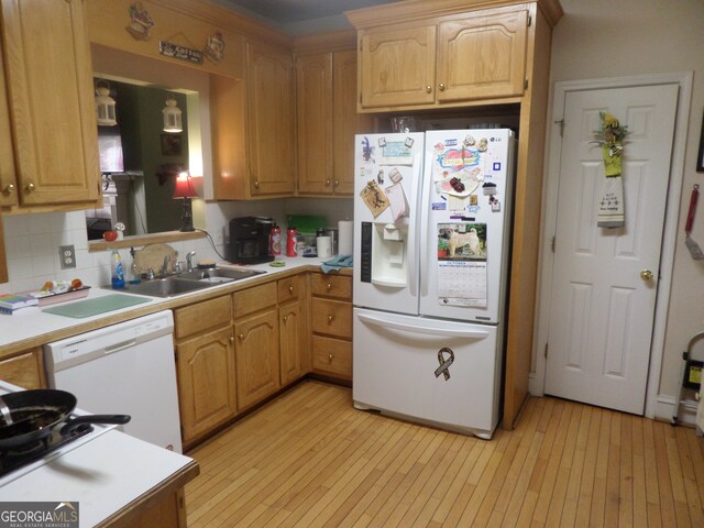 kitchen featuring white appliances, decorative backsplash, sink, and light wood-type flooring