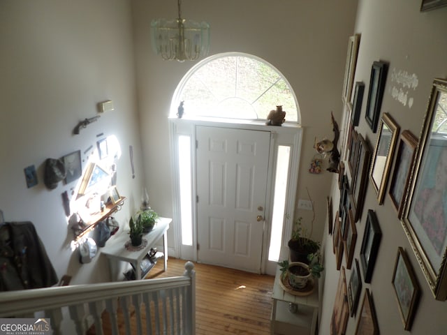 foyer entrance featuring a towering ceiling, hardwood / wood-style floors, and a chandelier