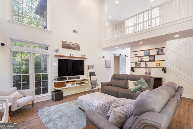 living room featuring a barn door, a towering ceiling, and a healthy amount of sunlight