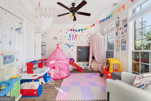 rec room with ceiling fan, hardwood / wood-style floors, and ornamental molding