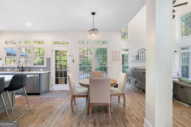 dining space featuring ceiling fan with notable chandelier, light hardwood / wood-style floors, and sink