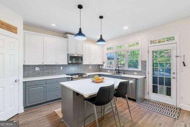 kitchen with a kitchen island, white cabinetry, appliances with stainless steel finishes, and light hardwood / wood-style flooring