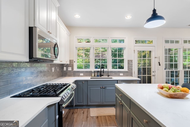 kitchen with white cabinets, appliances with stainless steel finishes, pendant lighting, and sink