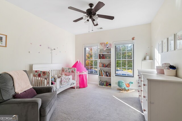 carpeted bedroom with a nursery area and ceiling fan