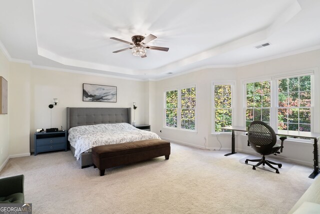 carpeted bedroom featuring ceiling fan, crown molding, and a tray ceiling