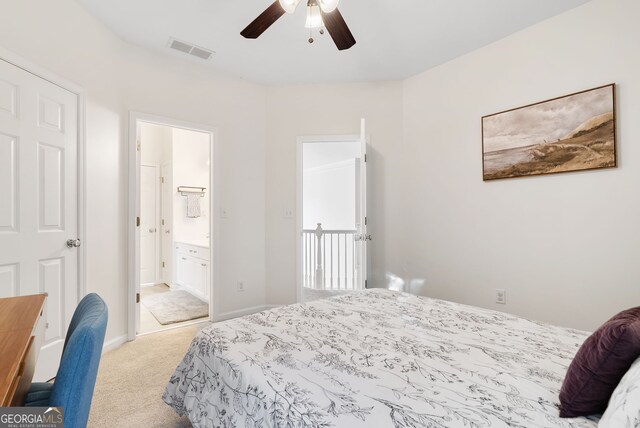 bedroom featuring ceiling fan, light colored carpet, and ensuite bath