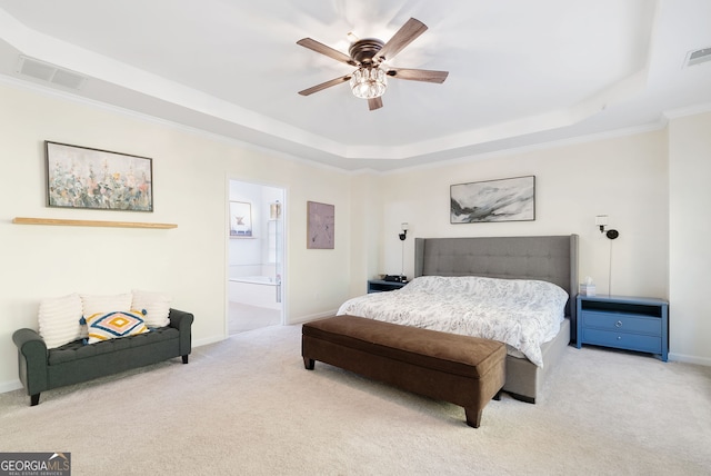 carpeted bedroom with a tray ceiling, ensuite bath, ceiling fan, and crown molding