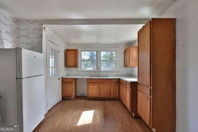 kitchen featuring white refrigerator, light wood-type flooring, and sink