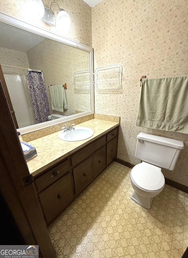 bathroom featuring wallpapered walls, toilet, and baseboards