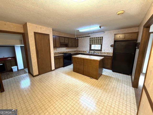 kitchen with black appliances, a center island, sink, and a textured ceiling