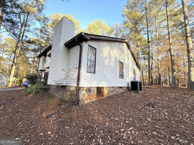 view of property exterior with a chimney, central AC, and crawl space