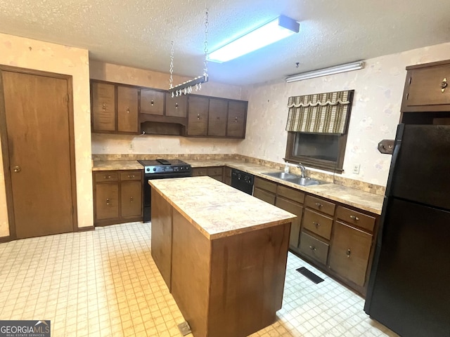 kitchen featuring light floors, a sink, black appliances, light countertops, and a center island