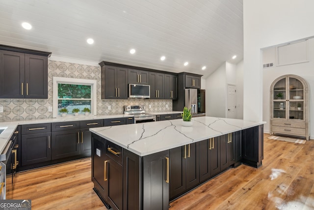 kitchen featuring stainless steel appliances, light hardwood / wood-style floors, a center island, and light stone countertops