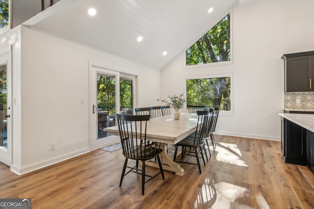 dining room featuring high vaulted ceiling, light hardwood / wood-style floors, and wood ceiling