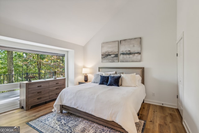 bedroom with high vaulted ceiling and hardwood / wood-style floors