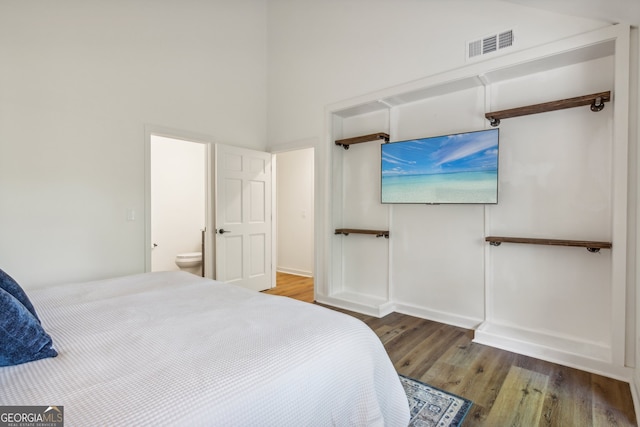 bedroom featuring hardwood / wood-style flooring, a towering ceiling, and ensuite bathroom