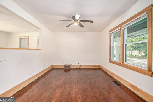 empty room with ceiling fan and dark hardwood / wood-style flooring