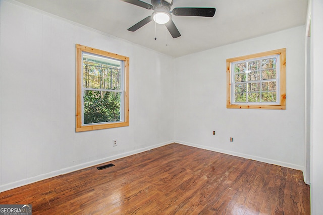 unfurnished room featuring plenty of natural light, ceiling fan, and dark wood-type flooring