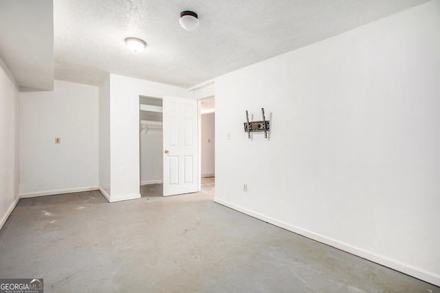 unfurnished bedroom with a textured ceiling, concrete floors, and a closet