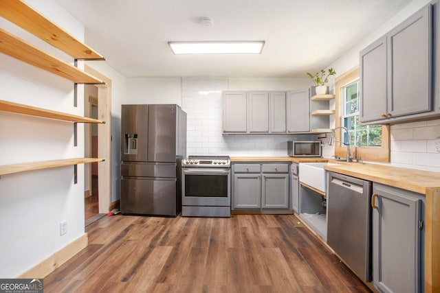 kitchen with wood counters, stainless steel appliances, gray cabinets, and dark hardwood / wood-style floors