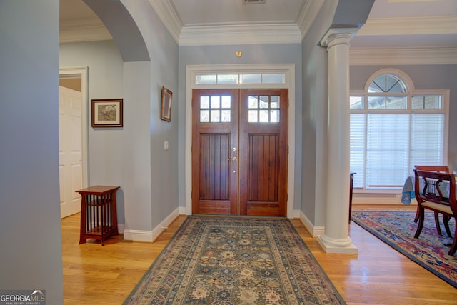 foyer with a wealth of natural light, ornamental molding, ornate columns, and light hardwood / wood-style floors