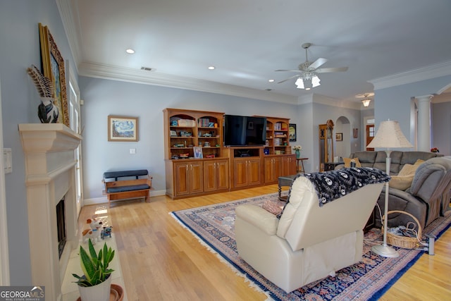 living room with crown molding, decorative columns, light hardwood / wood-style flooring, and ceiling fan