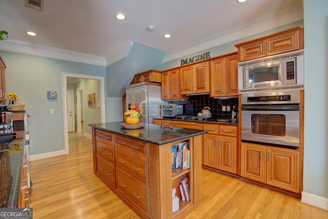 kitchen featuring decorative backsplash, dark stone countertops, a center island, light wood-type flooring, and appliances with stainless steel finishes