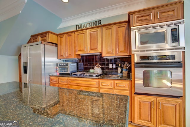 kitchen with appliances with stainless steel finishes, crown molding, dark stone countertops, and tasteful backsplash