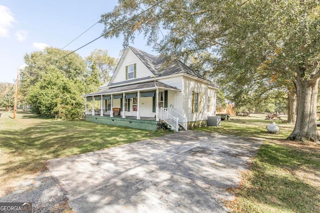 farmhouse with a porch, a front yard, and central air condition unit