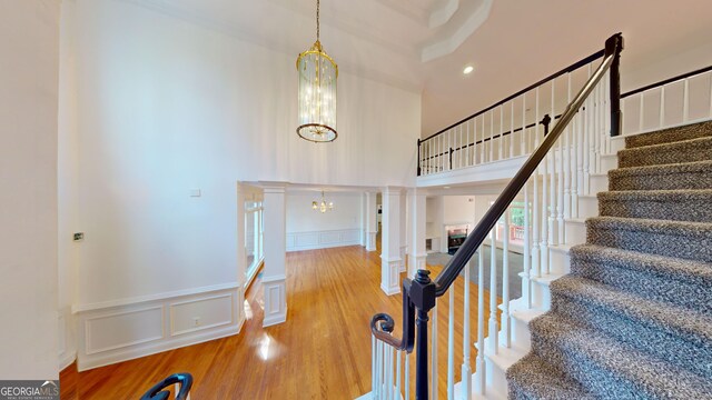 15 Greenridge Way, Newnan, GA 30265 - stairway with a decorative wall, a chandelier, a wainscoted wall, wood finished floors, and a towering ceiling