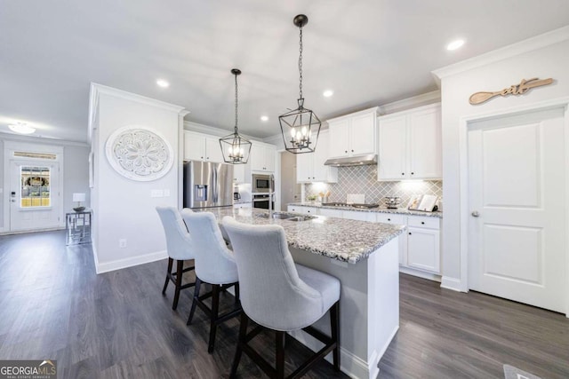 kitchen with appliances with stainless steel finishes, decorative light fixtures, a kitchen island with sink, white cabinets, and dark hardwood / wood-style flooring