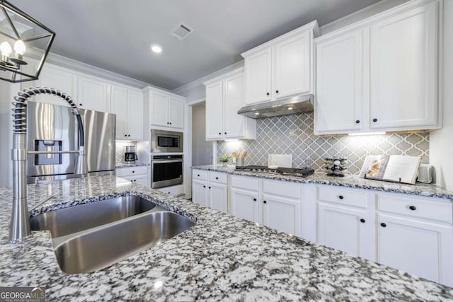 kitchen featuring hanging light fixtures, white cabinetry, decorative backsplash, and appliances with stainless steel finishes