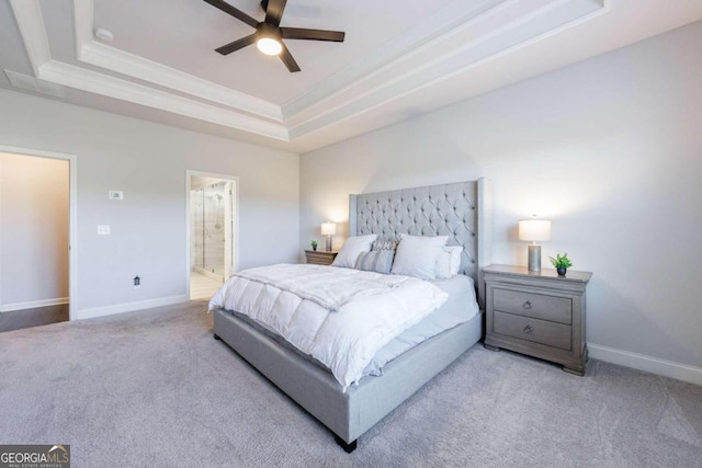 bedroom with ceiling fan, light carpet, and a tray ceiling