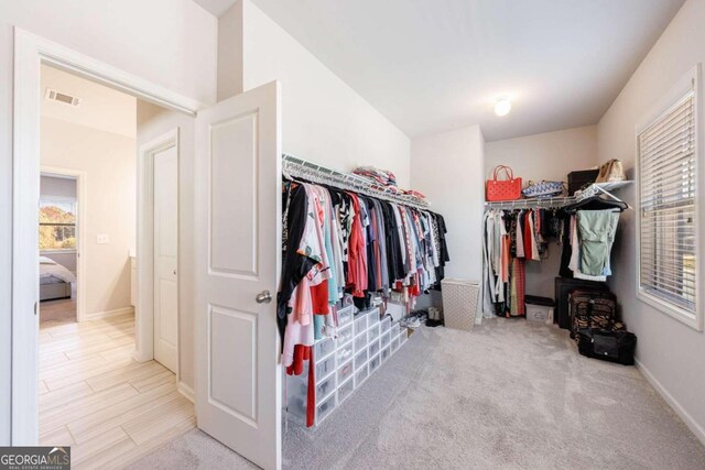 walk in closet featuring light colored carpet