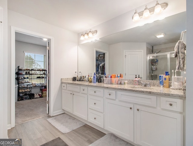 bathroom with hardwood / wood-style flooring, vanity, and an enclosed shower