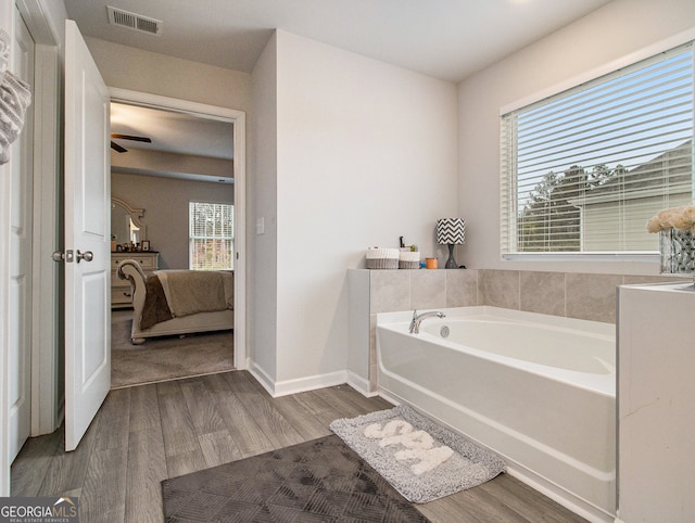 bathroom with a bathing tub, hardwood / wood-style flooring, and ceiling fan