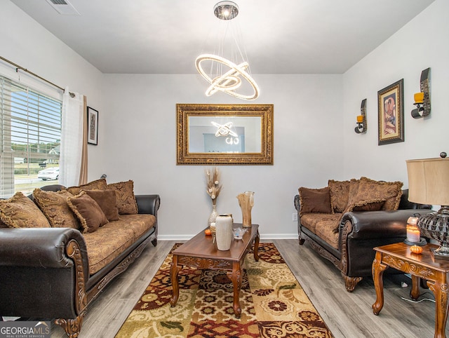 living room with light hardwood / wood-style floors and a notable chandelier