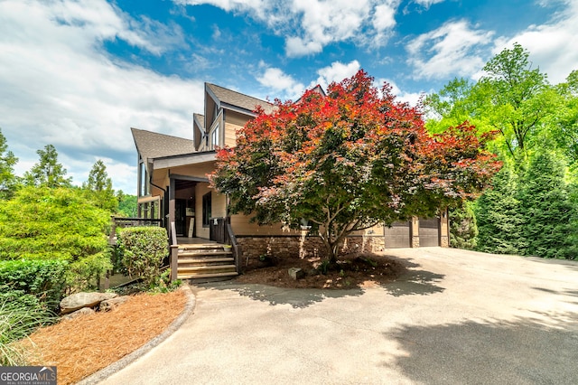 view of property hidden behind natural elements with covered porch and a garage