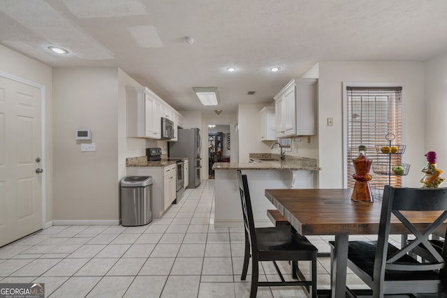 kitchen with appliances with stainless steel finishes, sink, white cabinetry, and a textured ceiling