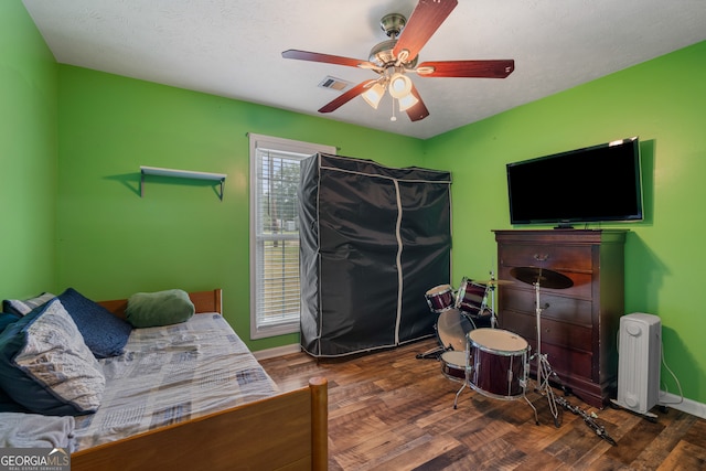 bedroom with dark hardwood / wood-style floors, a textured ceiling, and ceiling fan