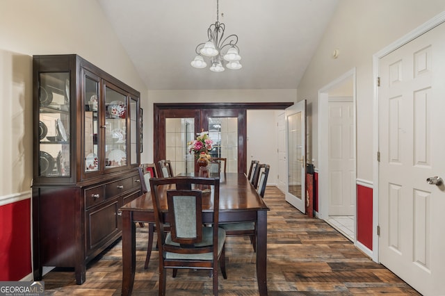 dining area with lofted ceiling, dark wood-type flooring, and an inviting chandelier