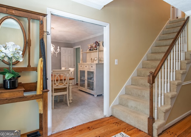 stairway with ornamental molding, hardwood / wood-style floors, and a chandelier